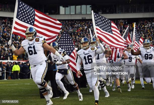 Players of the Navy Midshipmen of the US Naval Academy arrive waving the American flag prior to the annual Army-Navy football game at Lincoln...