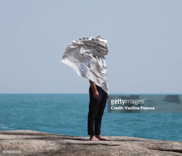 man covered with foil against sea background - technology curiosity stock pictures, royalty-free photos & images
