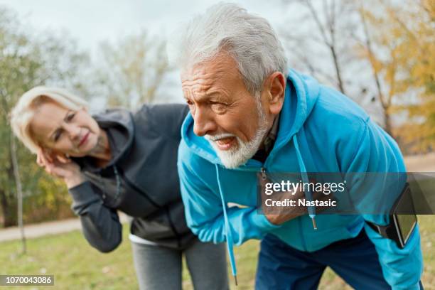 senior man suffering heart attack whilst jogging - chest imagens e fotografias de stock