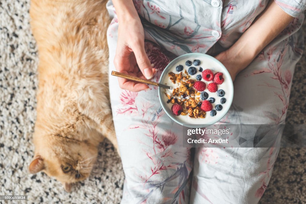 Eating yogurt with granola and berries. Female eating healthy breakfast