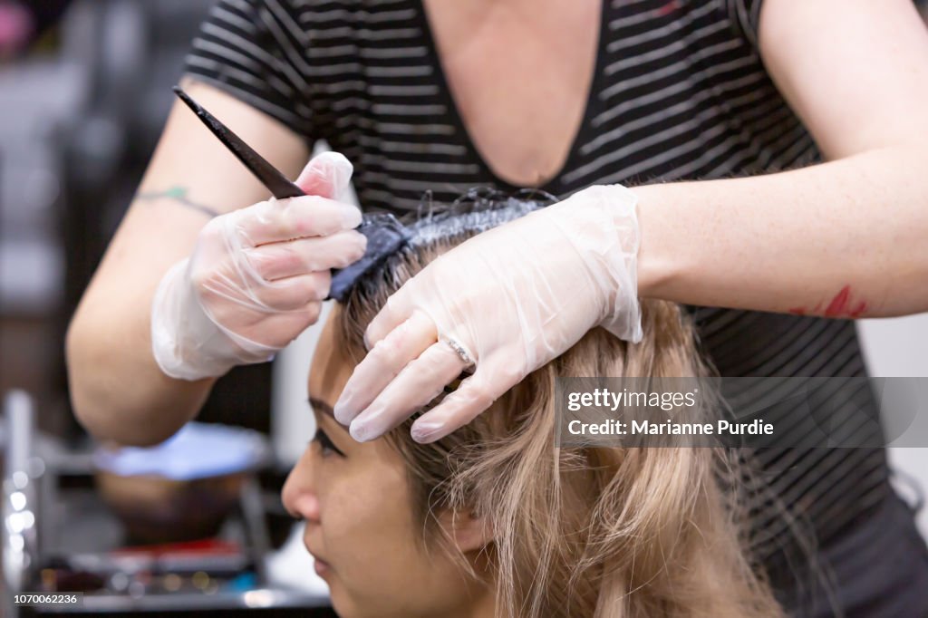A hairdresser having her hair dyed
