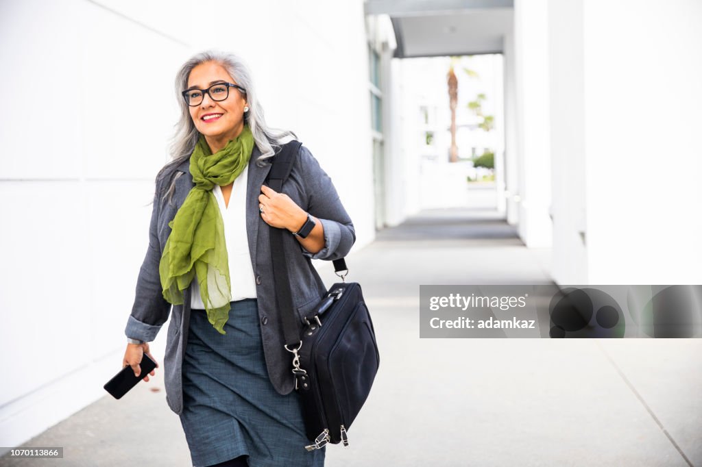 Senior hispanic businesswoman Walking down hallway