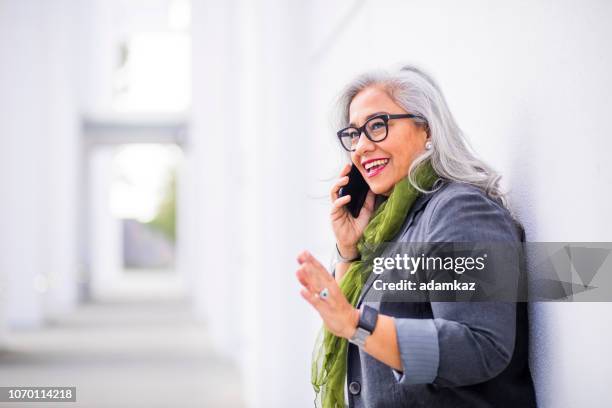 femme d’affaires hispanique senior sur le téléphone - call conference photos et images de collection