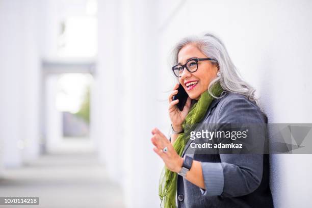 senior hispanic businesswoman on the phone - senior adult on phone stock pictures, royalty-free photos & images