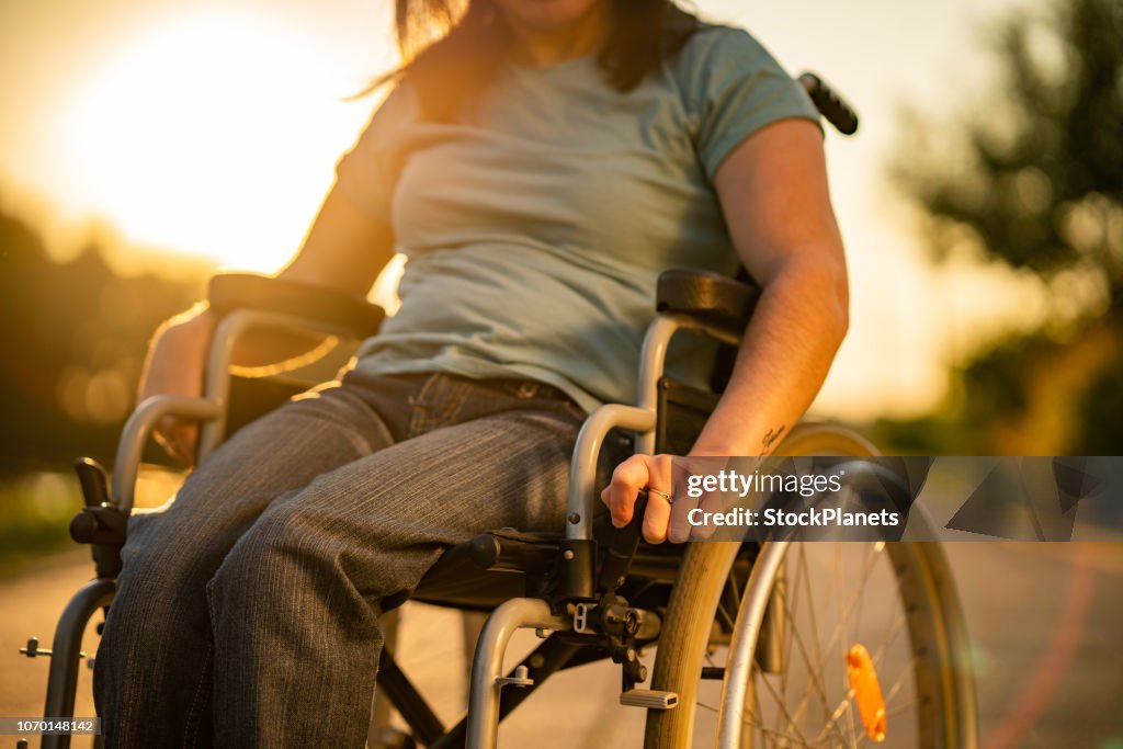 Unrecognizable women on a wheelchair at sunset