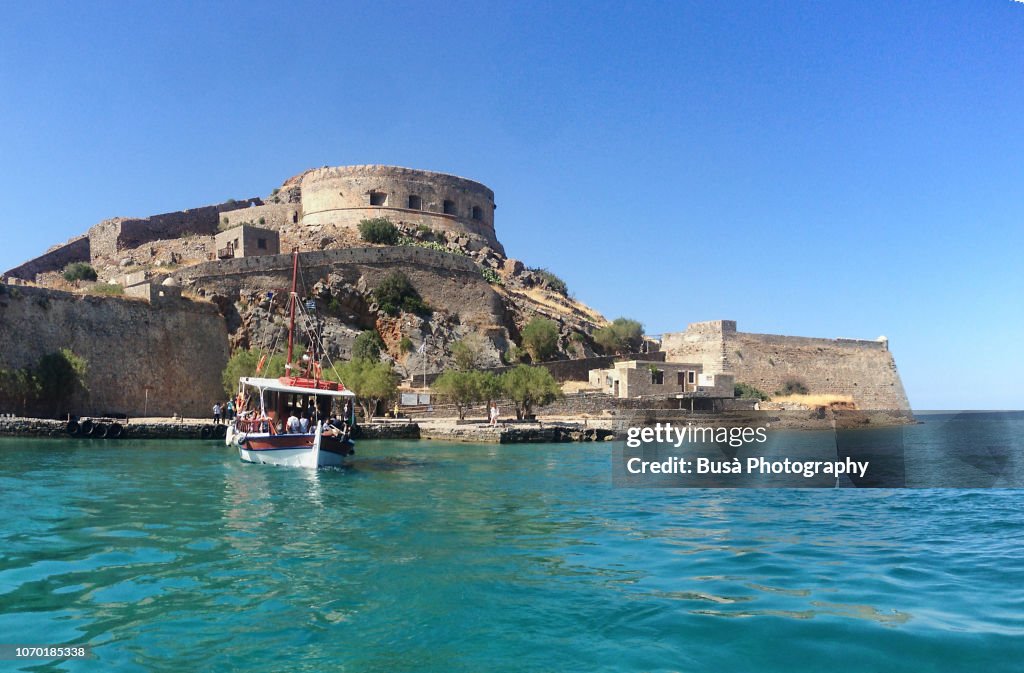 Tourist boat approaching the fortress of Spinalonga, in the island known as Kalydon (Καλυδών) in north-eastern Crete