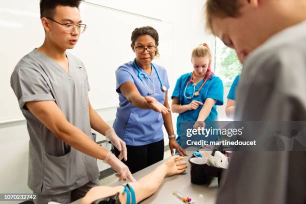 multi-ethnic group of students in college nursing class. - mannequin arm stock pictures, royalty-free photos & images