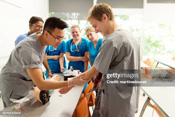 multi-ethnic group of students in college nursing class. - mannequin arm stock pictures, royalty-free photos & images