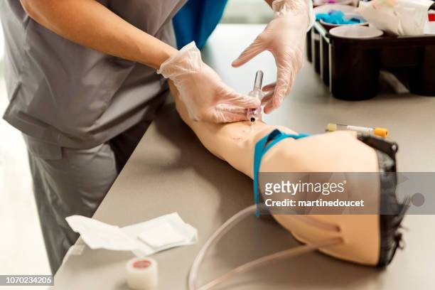 close-up on nursing student doing blood test on mannequin arm in college. - mannequin arm stock pictures, royalty-free photos & images