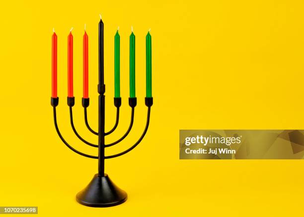 black kwanzaa candelabra with red, green, and black candles on yellow background. - kwanzaa fotografías e imágenes de stock