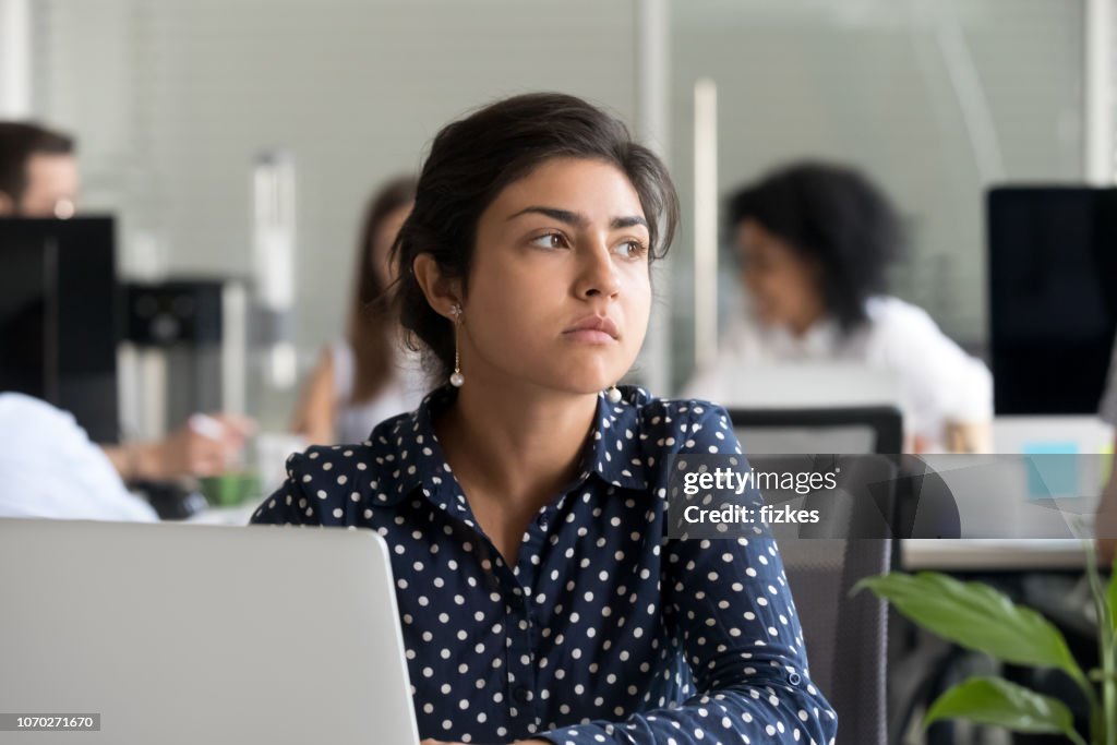 Thoughtful indian businesswoman looking away thinking of problem solution