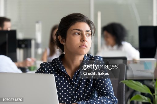 Thoughtful indian businesswoman looking away thinking of problem solution Thoughtful indian businesswoman looking away thinking of problem solution