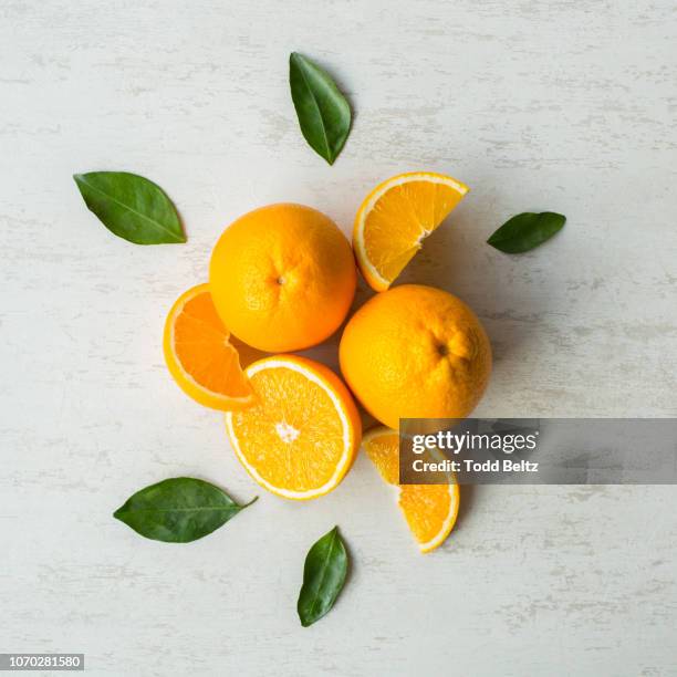 whole and cut oranges with the leaves from the orange tree on a white rustic background - stylisme culinaire photos et images de collection