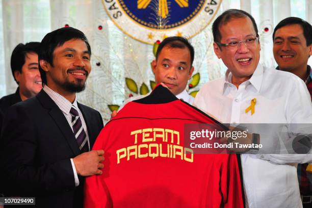 Boxer and congressman, Manny Pacquiao gives President Benigno Aquino III a shirt and memorabilia following his win of the WBC super welterweight...