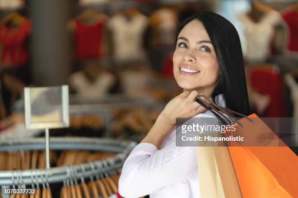 vacker latinamerikansk kvinna på en klädaffär som tittar bort mycket tankeväckande men lycklig - latin american and hispanic shopping bags bildbanksfoton och bilder