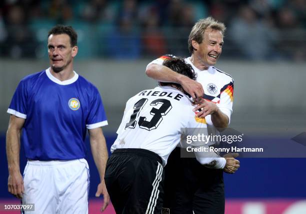 Juergen Klinsmann and Karlheinz Riedle of the World Champion 1990 celebrate their teams first goal next to Andreas Wagenhaus of the DFV Legend during...
