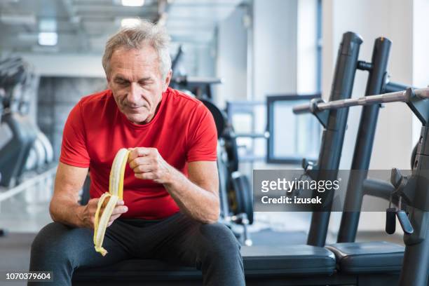 senior man eating banana during rehabilitation in gym - exercise and diet stock pictures, royalty-free photos & images