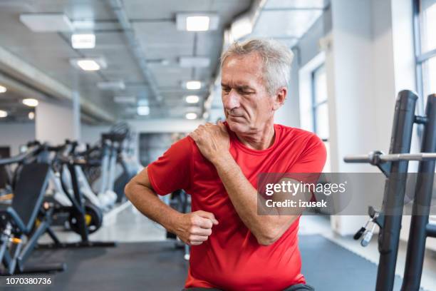 リハビリテーション センターでの肩の痛みから苦しんでいる年配の男性 - fitness center ストックフォトと画像