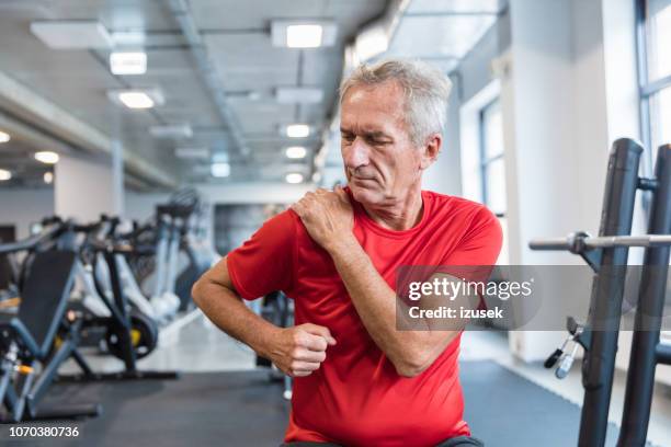senior man die lijden aan pijn in de schouder bij revalidatiecentrum - over shoulder man stockfoto's en -beelden