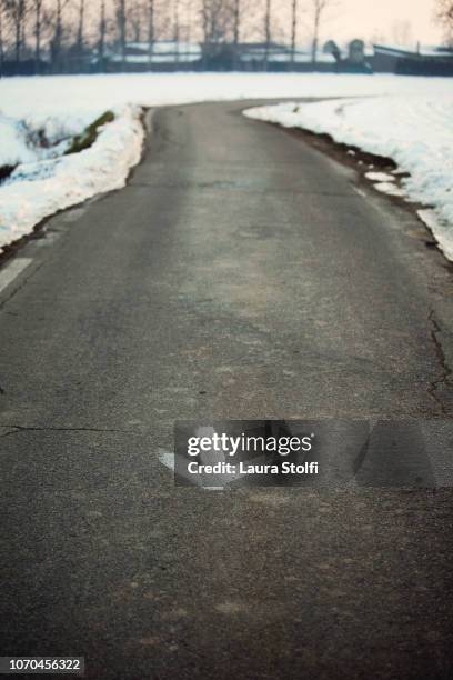 direction arrow hand drawn with white paint on coutryside road asphalt in snowy landscape - arrows landscapes stock pictures, royalty-free photos & images