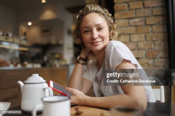 a 40 years old woman with her cell phone in a parisian cafe - 40 44 years woman caucasian stockfoto's en -beelden