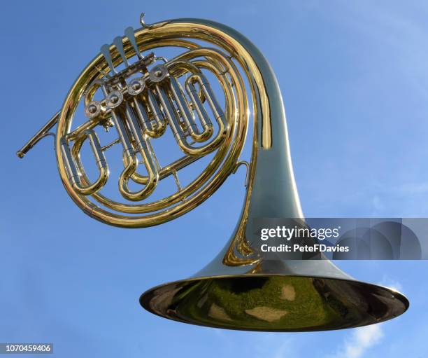 french horn against a blue sky. - trompa fotografías e imágenes de stock