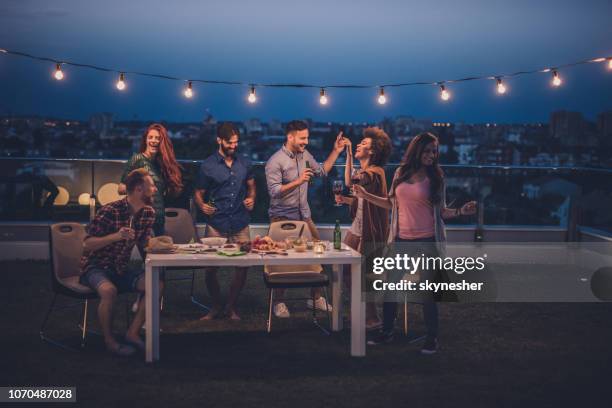 young happy people having fun while dancing on a night party at penthouse balcony. - patio party stock pictures, royalty-free photos & images