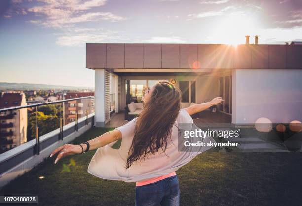 carefree woman spinning on a penthouse balcony. - rooftop garden stock pictures, royalty-free photos & images