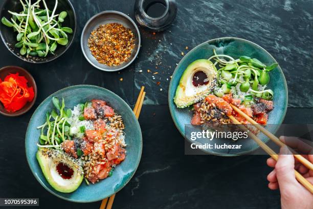 man eating poke bowls with ponzu dressing - comida asiática imagens e fotografias de stock