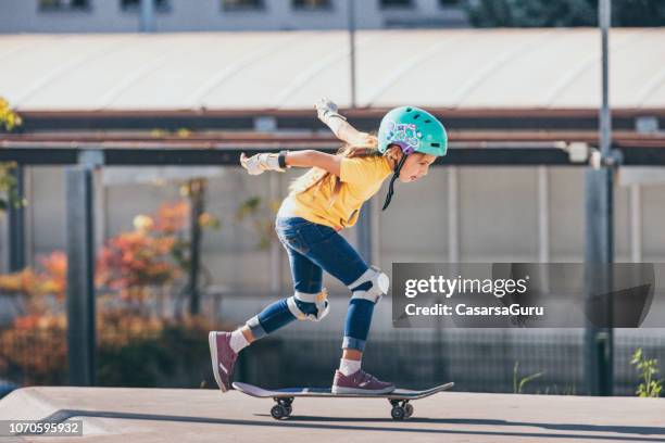 jovencita montando un monopatín al aire libre - monopatín artículos deportivos fotografías e imágenes de stock