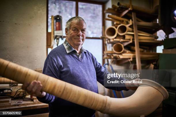 portrait of senior man in workshop holding alpenhorn - alphorn stock-fotos und bilder