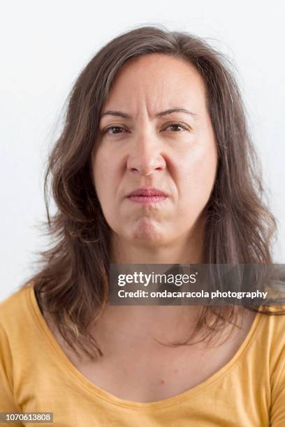 a middle-aged woman with an expression of worry and disgust - angry faces stock-fotos und bilder