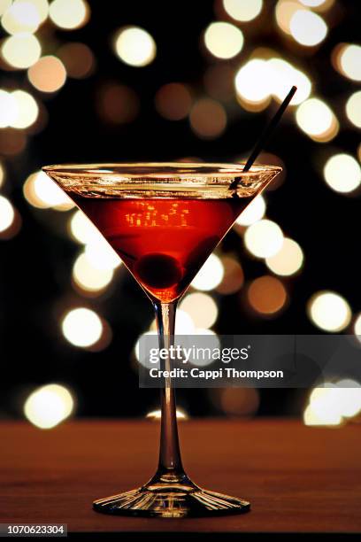 holiday martini on bar counter with christmas lights in background - cocktail counter stock pictures, royalty-free photos & images