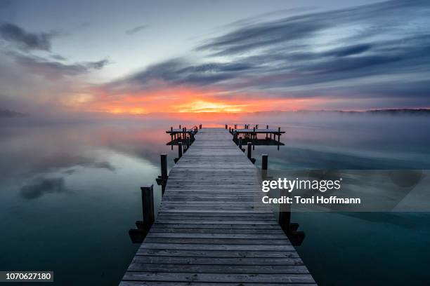 beautiful sunrise at lake wörthsee - holzsteg stock-fotos und bilder