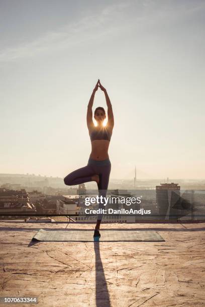 woman doing yoga on the rooftop - upright position stock pictures, royalty-free photos & images