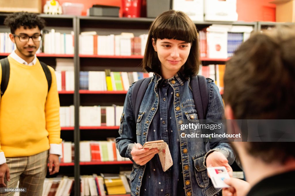 Multi-ethnic students buying books in student association classroom.