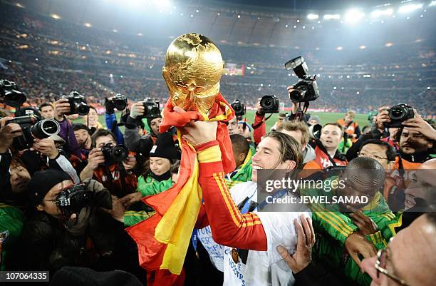 Spain's defender Sergio Ramos holds up the trophy, the base of it wrapped in the Spanish national flag, during the award ceremony following their...