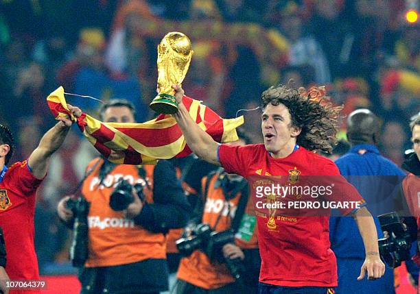 Spain's defender Carles Puyol runs with the trophy as he celebrates winning the 2010 World Cup football final Netherlands vs. Spain on July 11, 2010...