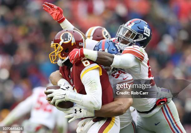 Quarterback Mark Sanchez of the Washington Redskins is sacked by outside linebacker Olivier Vernon and linebacker Lorenzo Carter of the New York...