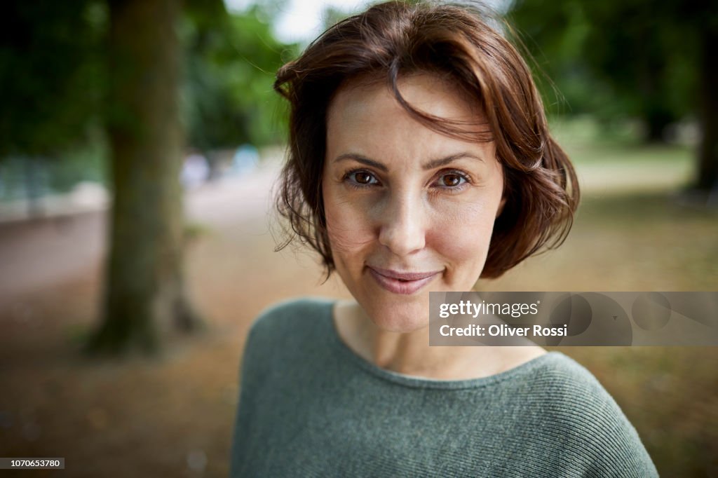 Portrait of smiling brunette woman in a park