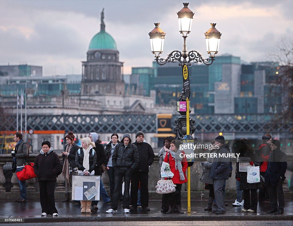 Commuters wait at a bus stop in the earl