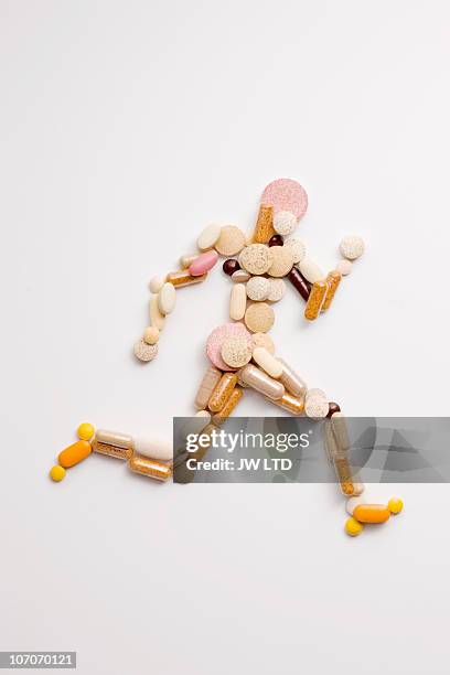 vitamin pills in shape of man running - steroid stock-fotos und bilder