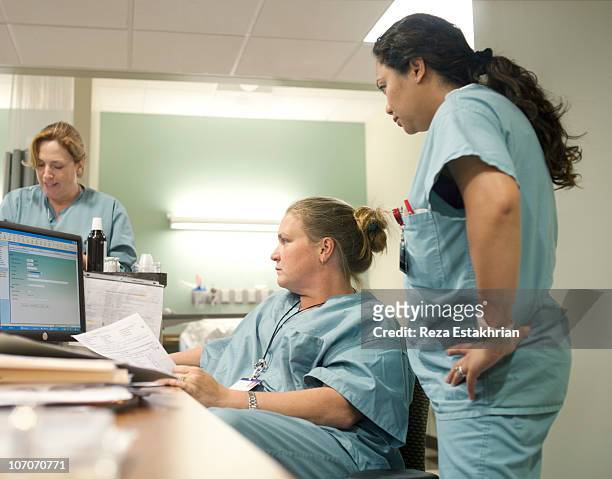 nurses check information in computer - schwesterntisch stock-fotos und bilder