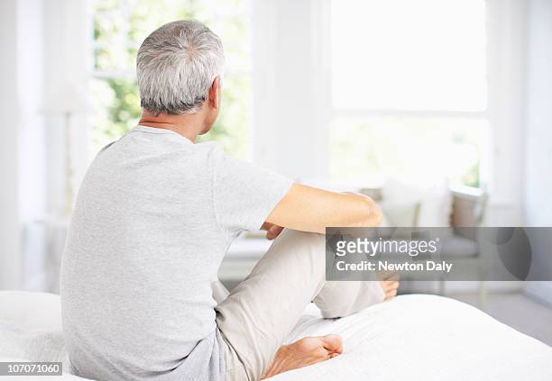 senior man relaxing on bed, rear view - grey hair man stock pictures, royalty-free photos & images