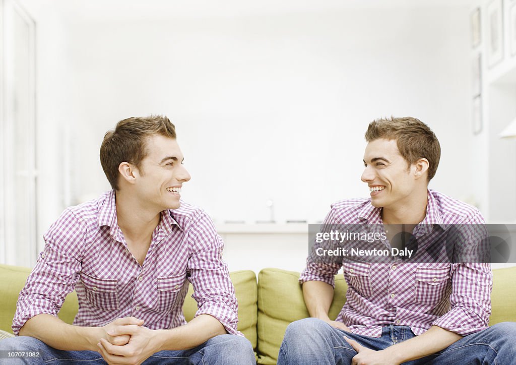 Twins sitting on sofa, smiling
