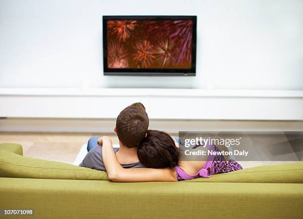 young couple watching television, rear view - couple sofa stock pictures, royalty-free photos & images