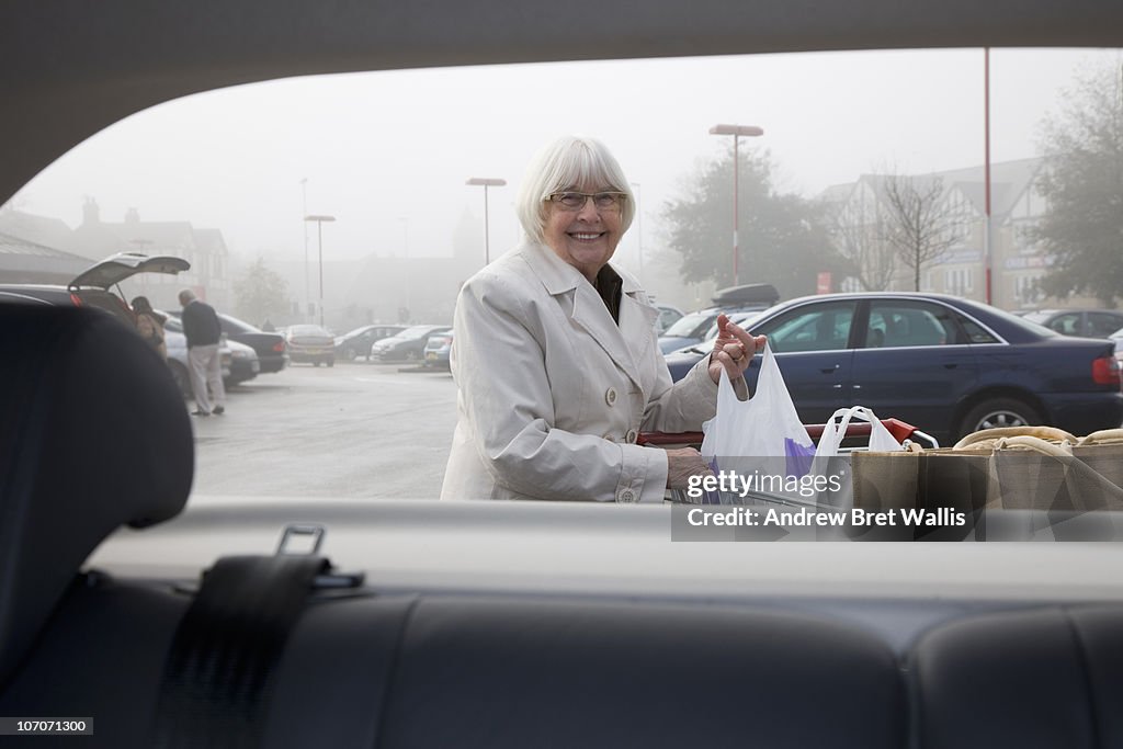 Senior woman loading shopping into a car