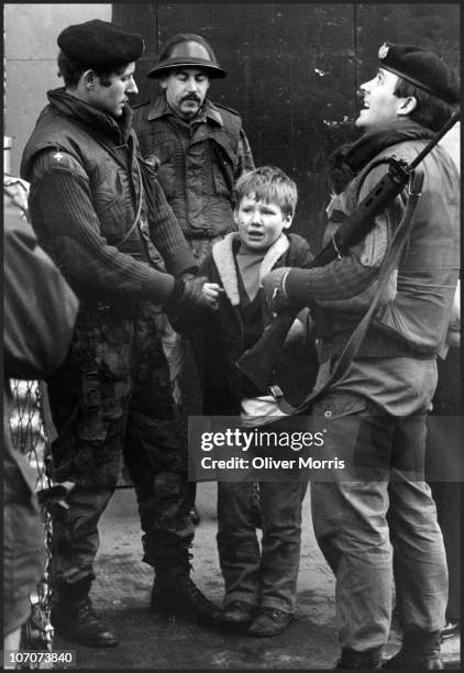 Young boy is held by British soldiers from the Gloucester Regiment after he was caught in the act of hurling stones at a Saracen Armoured Personal...