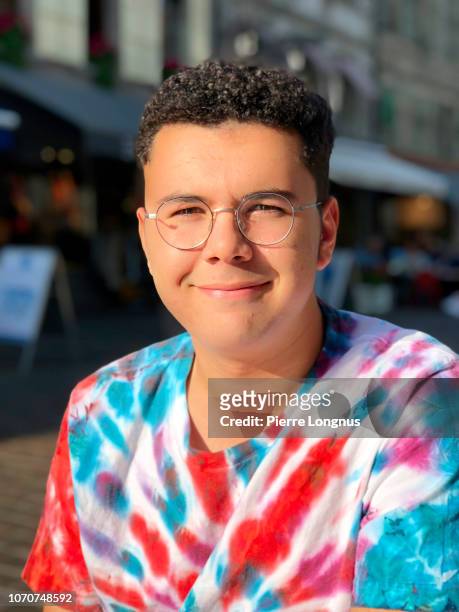 portrait of a 15-year-old boy with curly brown hair, wearing eyeglasses and a tie-dye t-shirt - tie dye stock pictures, royalty-free photos & images