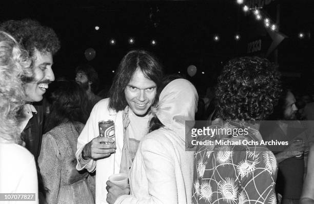 Canadian musician Neil Young chats with singer Nicolette Larson at the premiere party for his concert movie 'Rust Never Sleeps' held on the lot of...